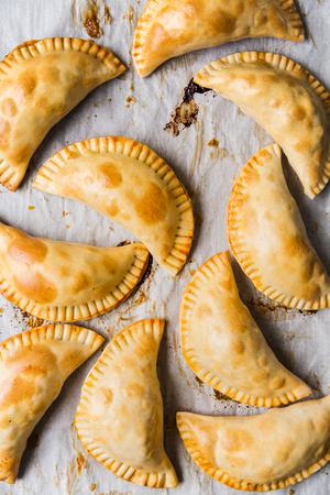 golden brown shredded chicken empanadas on a baking sheet