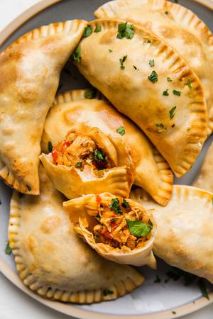 chicken empanadas on a plate one broken open to see the filling