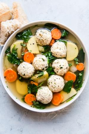 a bowl of homemade chicken meatball and vegetable soup  served with crusty bread