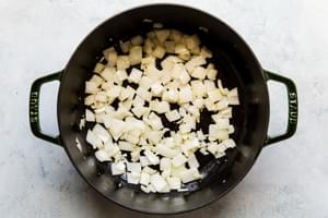 onions and garlic being cooked in olive oil in a large soup pot
