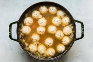 onion, garlic, chicken stock, fennel seeds, salt, carrots, potatoes and chicken meatballs cooking in a pot