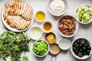 ingredients laid out for waldorf salad: grilled chicken, grapes, apples, celery, candied walnuts
