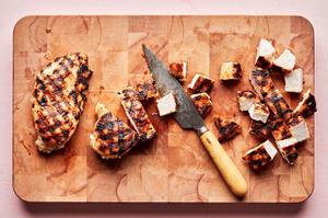 grilled chicken being sliced on a cutting board