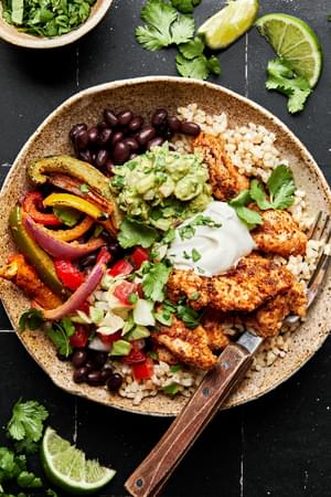 chicken fajita burrito bowl with beans, rice, peppers, onions and topped with guac and sour cream