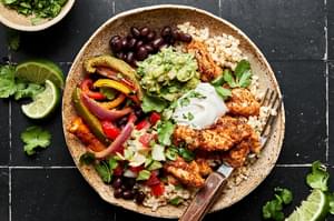 chicken fajita burrito bowl with beans, rice, peppers, onions and topped with guac and sour cream