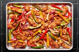 raw chicken, peppers and onions seasoned with homemade taco seasoning on a baking sheet