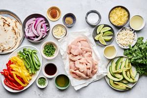 chicken, peppers, onions, avocado, cilantro, tortillas, cilantro, spices and limes wedges in prep bowls
