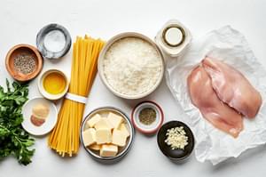 chicken, spices, fettuccine, butter, olive oil, parsley, heavy cream, parmesan and parsley in bowls to make chicken alfredo