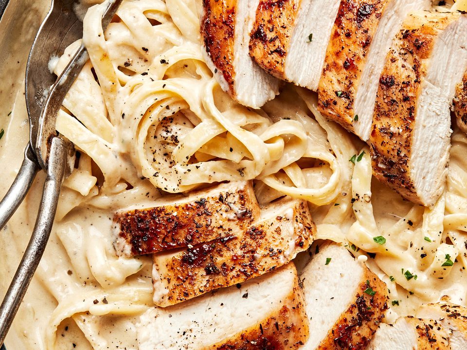 Homemade chicken fettuccine alfredo in a serving bowl with serving spoons