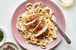 Homemade chicken fettuccine alfredo in a bowl with a fork