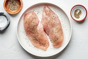 raw chicken being seasoned with salt, pepper and italian seasoning to use for chicken fettuccine alfredo