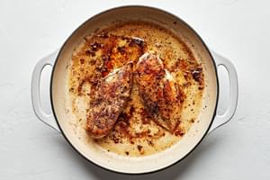 chicken breast seasoned with salt, pepper and italian seasoning being cooked in a skillet with olive oil and butter