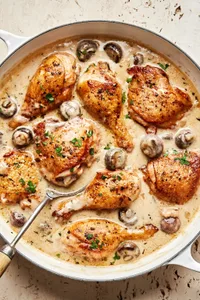 chicken fricassee made with mushrooms, onion, garlic, thyme, bay leaves, nutmeg and sprinkled with parsley in a skillet