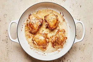 4 bone in chicken thighs seasoned with salt and pepper cooking in melted butter in a skillet