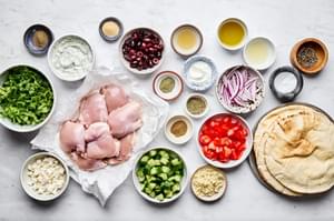 chicken, cucumbers, pita, garlic, olive oil, spices, tomatoes and red onions in prep bowls to make chicken gyros