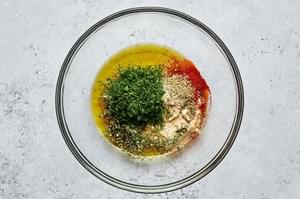 lemon juice, olive oil, dill, oregano, basil, paprika, onion powder, garlic powder, salt, and pepper in a glass bowl