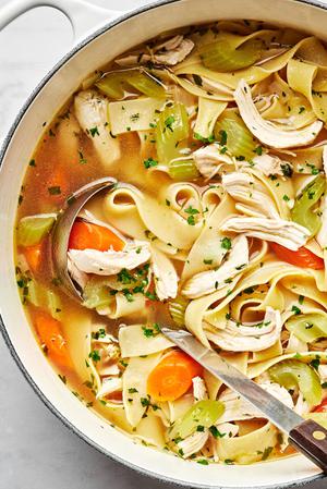 a pot of chicken noodle soup made with onion, celery, carrots, garlic, chicken stock, bay leaves, chicken, egg noodles & salt