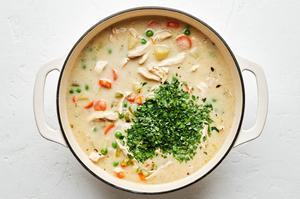 minced thyme and parsley being added to a pot of homemade chicken pot pie soup