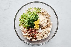 shredded chicken, mayo, dijon, spices, celery, pecans, parsley, lemon zest & lemon juice being mixed in a bowl