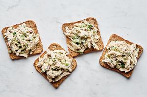 homemade chicken salad being put on top of bread to make sandwiches