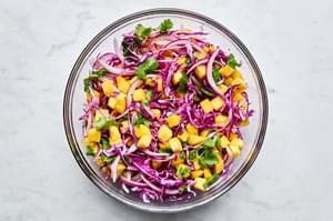 mango slaw in a bowl made with mangos, red onion, cabbage, cilantro, lime juice, and salt