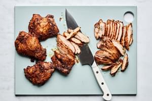 baked chicken thighs being sliced on a cutting board