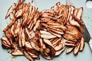 baked chicken thighs being sliced on a cutting board