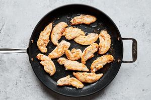 chicken tenders seasoned with salt being browned in butter in a skillet