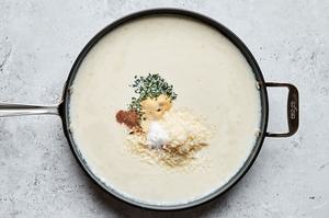cream sauce in a skillet made with butter, flour, cream, broth, thyme, garlic & onion powder, nutmeg, salt & parmesan
