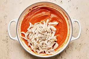 shredded chicken being tossed with homemake smoky tinga sauce to make flavorful chicken tinga tacos