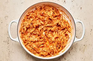 A pot filled with smoky chicken tinga, featuring shredded chicken simmered in a rich tomato and chipotle sauce