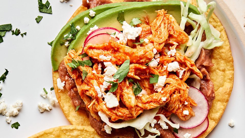 2 chicken tinga tacos served on corn tortillas topped with shredded cabbage, radishes, cotija and sliced avocado