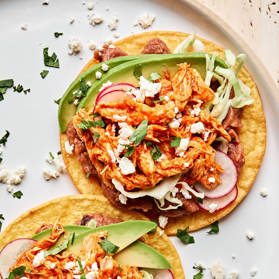 2 chicken tinga tacos served on corn tortillas topped with shredded cabbage, radishes, cotija and sliced avocado