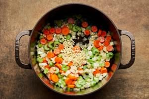 onion, carrots, celery and garlic being cooked in butter in a large pot