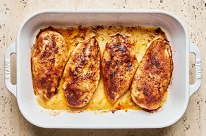 Baked chicken coated in a rich, golden-brown spice rub, in a baking dish fresh from the oven