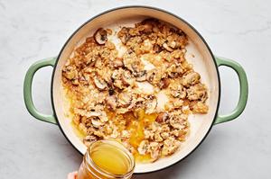 chicken broth being added to a skillet with white wine, flour, mushrooms, onion, garlic and butter