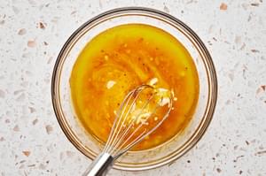 olive oil, vinegar, clementine zest, clementine juice, honey, Dijon, shallots, salt, & pepper being whisked in a glass bowl
