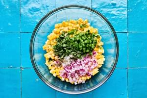 cooked corn, cilantro, onion, jalapeño, lime juice, salt and pepper being combined in a bowl