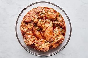 chicken marinating in olive oil, garlic, honey, lime zest, lime juice, cilantro, chili powder, salt, and pepper in a bowl