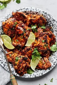cilantro lime chicken thighs on a serving platter garnished with cilantro and lime wedges