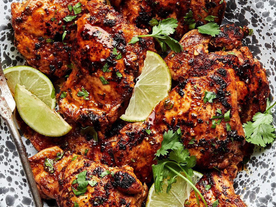 cilantro lime chicken thighs on a serving platter garnished with cilantro and lime wedges