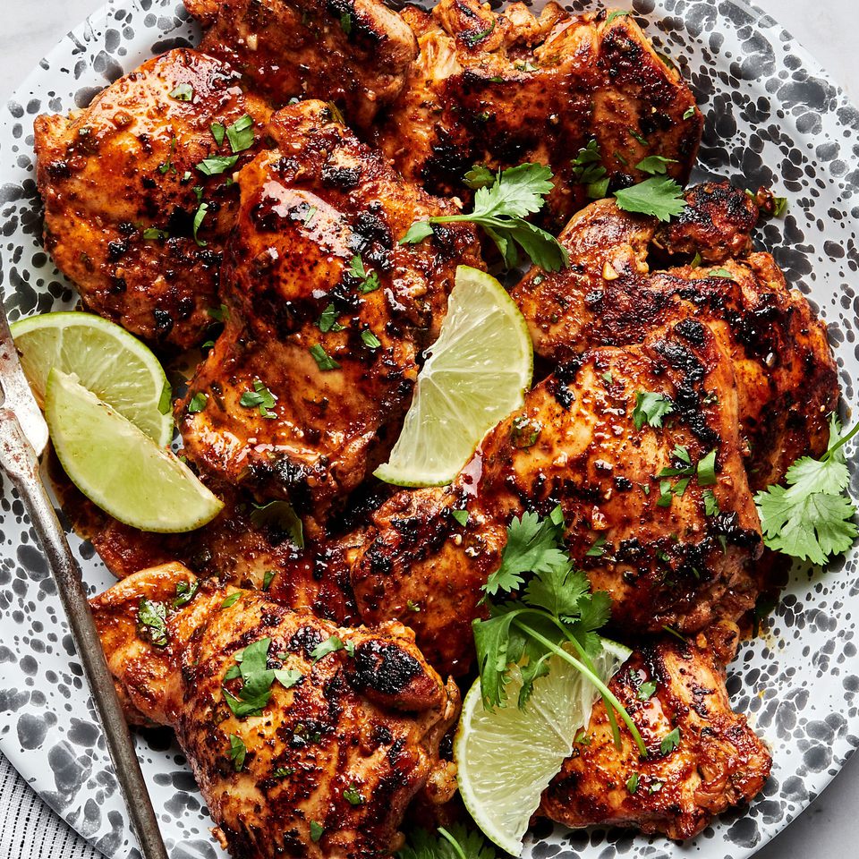 cilantro lime chicken thighs on a serving platter garnished with cilantro and lime wedges