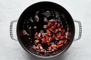 bacon being cooked in melted butter in a pot