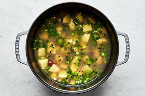 reserved clam water, cooked bacon, scallions, garlic, jalapeños, potatoes, salt and pepper being cooked in a large pot