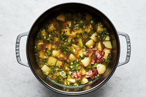 reserved clam water, cooked bacon, scallions, garlic, jalapeños, potatoes, salt and pepper being cooked in a large pot