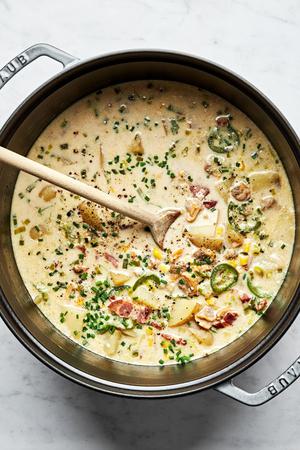 a pot of homemade clam chowder made with potatoes, scallions, bacon, jalapeños, corn, heavy cream and spices
