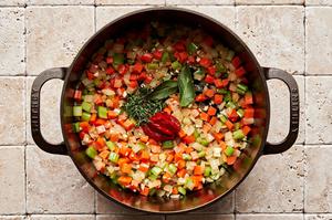onions, celery, carrots, tomato paste, bay leaves and thyme cooking in a pot