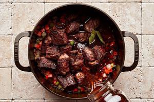 beef stock being added to beef stew in a pot