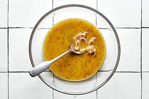 sliced shallots, stone-ground mustard, honey, olive oil, white wine vinegar, salt & pepper being stirred together in a bowl