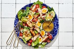 classic cobb salad made with romaine, chicken, hard boiled eggs, bacon, tomatoes, blue cheese, avocado & shallot vinaigrette